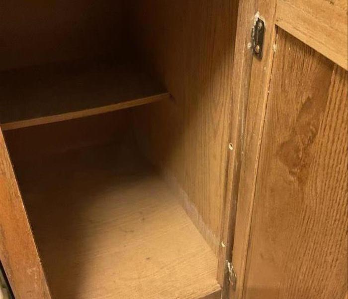 A picture of a cabinet in someone's kitchen with water damage. 